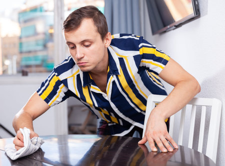 Confident man wiping surfaces in apartment