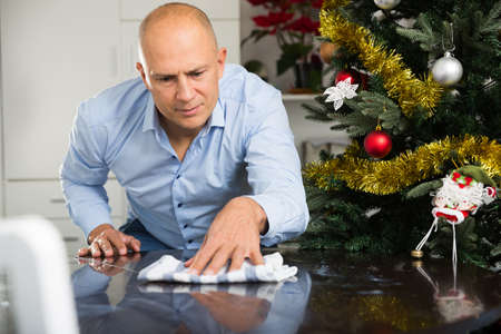Positive man wipes the table before Christmasの写真素材