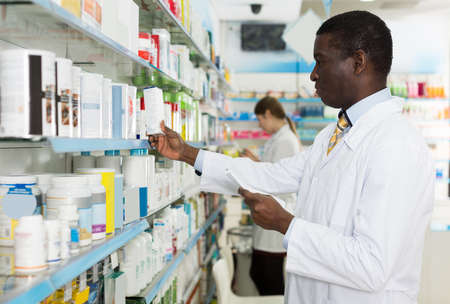 male pharmacist picking up prescription medicinesの写真素材