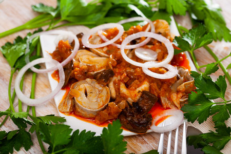 Marinated herring with mushrooms and tomato sauce on plate