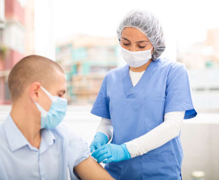 Professional nurse giving vaccine injection to manの写真素材
