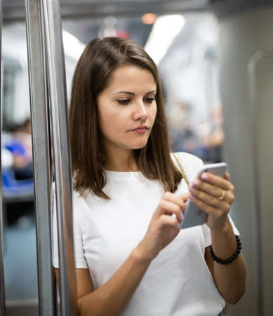 Woman holding smartphone in subway carの写真素材