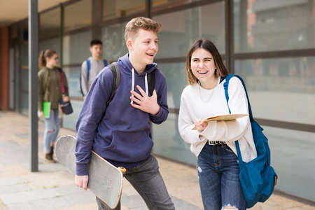 Girl and guy are discussing student issues on streetの写真素材