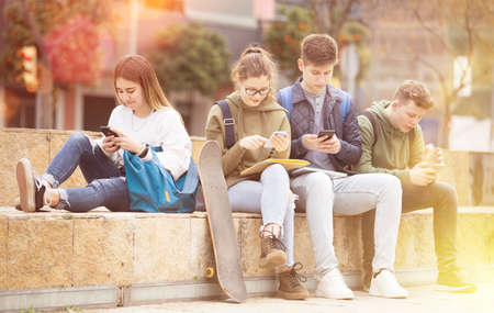 Group of teens using smartphones outdoorsの写真素材