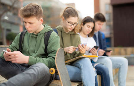 Teenagers are playing on smartphone on streetの写真素材