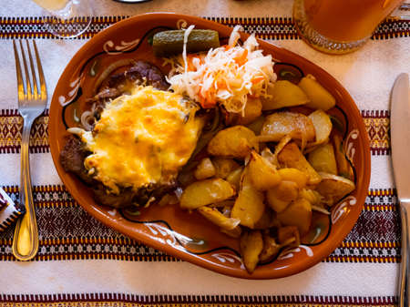 Dish of pork in Poltava with fried potatoes, pickled cabbage and cucumberの写真素材