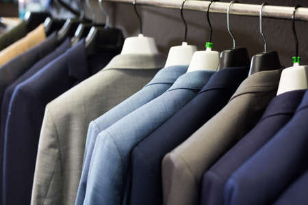 Men suits on hanger racks in shopの写真素材