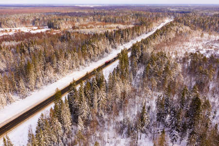 Winter landscape with road surrounded by snow covered woodlandの写真素材