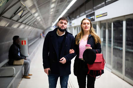 Young man with girlfriend walking on underground stationの写真素材