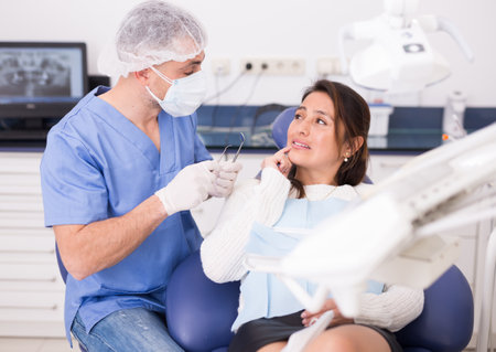 Woman complains of toothache to dentistの写真素材