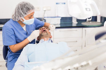 Female dentist in face mask with male patientの写真素材