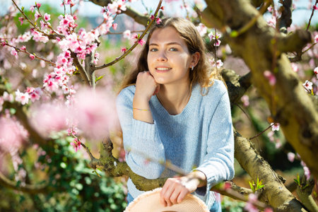 Portrait of happy girl in blooming garden on bright sunny day
