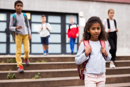 Smiling schoolgirl standing on the street, kids on background