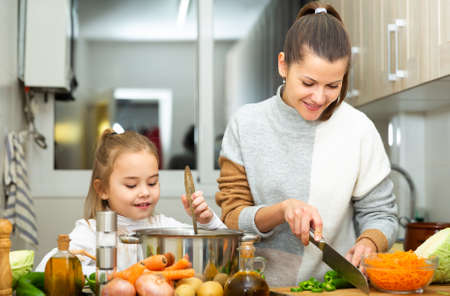 Mother and little daughter preparing soup together at home,の写真素材