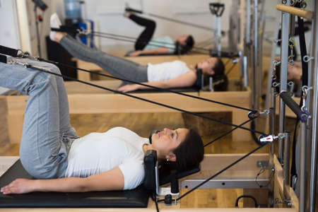 Young Hispanic woman performing pilates on reformer in fitness studioの写真素材
