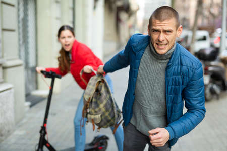 Bandit man is stole the bagpack from female on the streetの写真素材