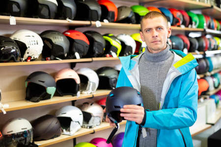 Man chooses helmet in a sports equipment storeの写真素材