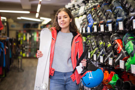 Girl in skiing outfit satisfied with choice in modern store of sports equipmentの写真素材