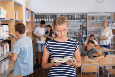Schoolgirl holding books in library.の写真素材