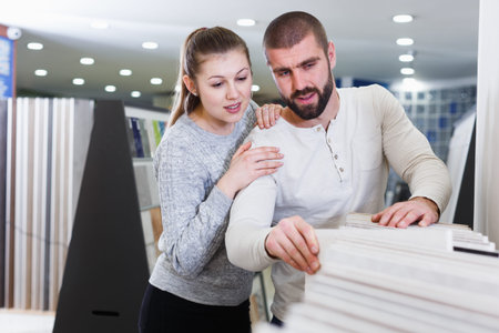 Positive couple choosing kitchen ceramic tile in storeの写真素材