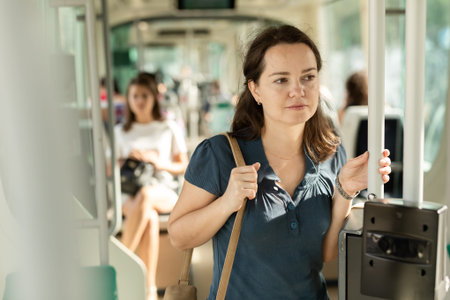Portrait of cheerful woman passenger standing in public bus