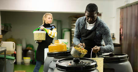 Food factory workers take olives from barrels for packing in plastic containersの写真素材