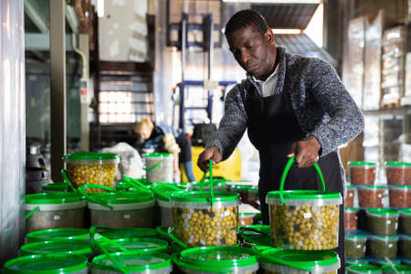 Man arranging plastic buckets with pickled olivesの写真素材