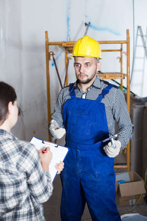 Repairman with spatula is clarifying details from clientの写真素材