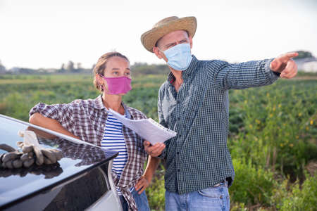 Farmers in masks discussing documents near carの写真素材