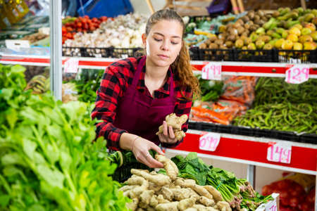 Smiling female seller lay out ginger on the counterの写真素材