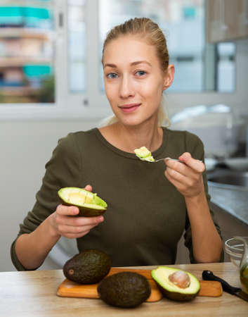 Portrait of girl with avocado in home kitchenの写真素材