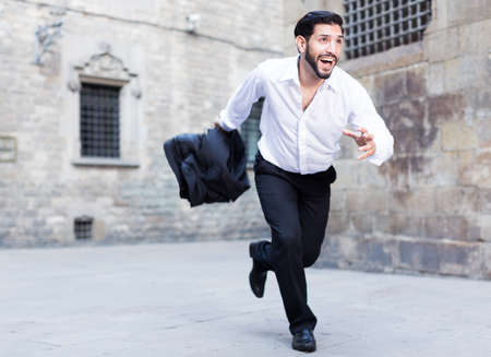 Expressive man running past old cityの写真素材