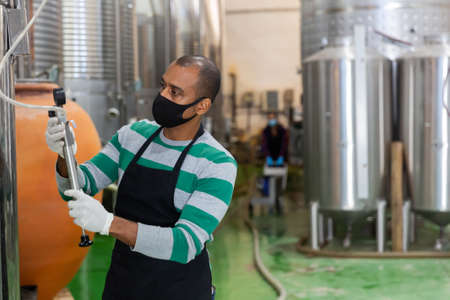 Male worker in mask working at wineryの写真素材