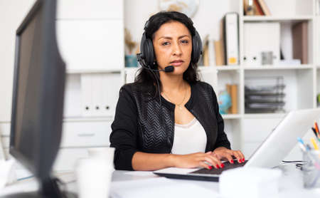 Female customer support phone operator with headphones during workの写真素材