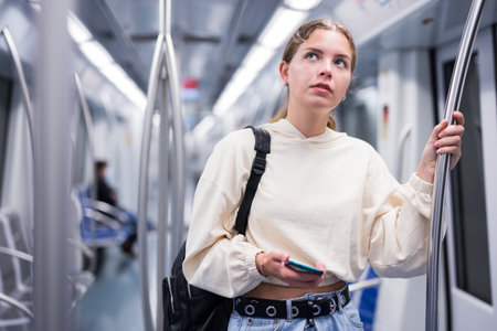 Portrait of a pensive girl with a mobile phone on a subway trainの写真素材