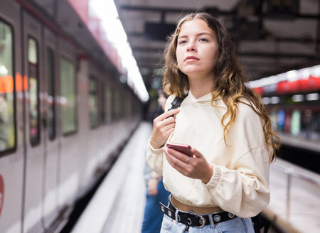 Young european female with mobile waiting the metroの写真素材