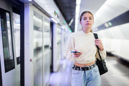 Young european female with mobile waiting the metroの写真素材