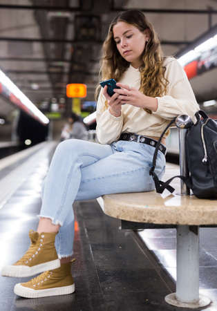 Young attractive girl in jeans waiting for subway train on a platformの写真素材
