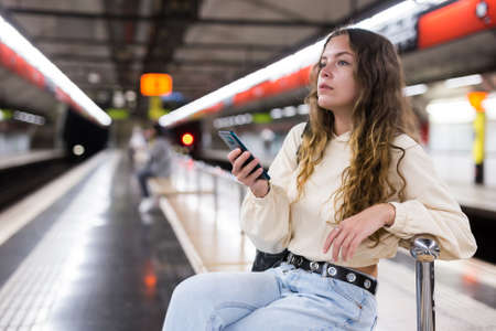 Young attractive girl in jeans waiting for subway train on a platformの写真素材