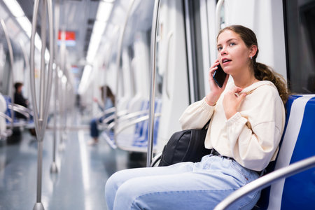Portrait of woman holding smart phone in a subway trainの写真素材