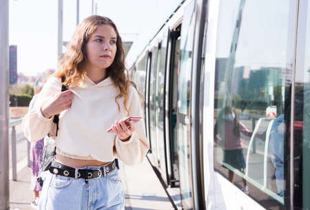Woman waiting for tram on platform of public transport stationの写真素材
