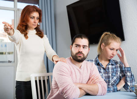 Portrait of sad mature woman trying to talk with adult children in homeの写真素材