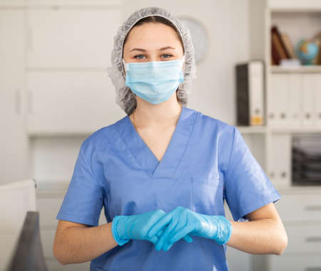 Masked girl nurse working in a hospital stands in residents an officeの写真素材