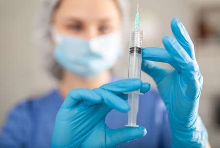 Female nurse in mask holding syringe for injectionの写真素材