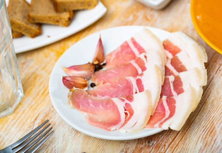 Sliced salted streaky pork bacon with garlic cloves