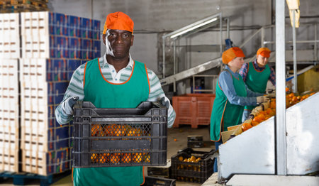 Man carrying box with mandarins in storage