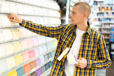 Young male customer choosing paint color for renovation worksの写真素材