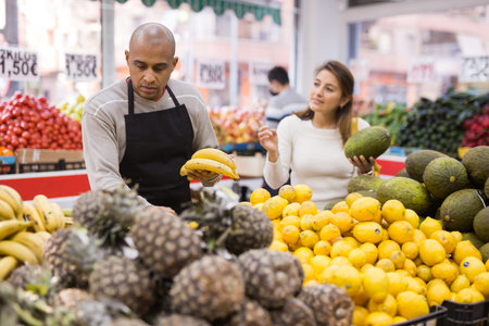 Friendly grocery store employee lays ripe bananas on counter