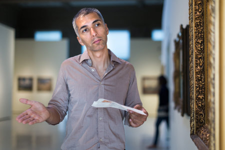 Adult male is visiting at the pictures exposition with brochure