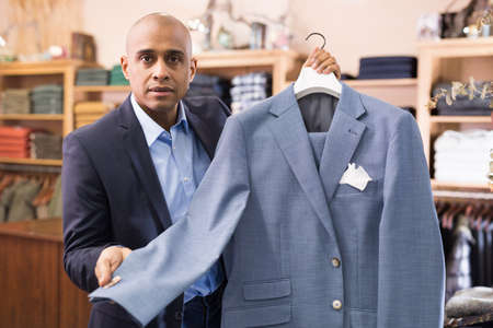 Friendly salesman offering suit in menswear boutiqueの写真素材